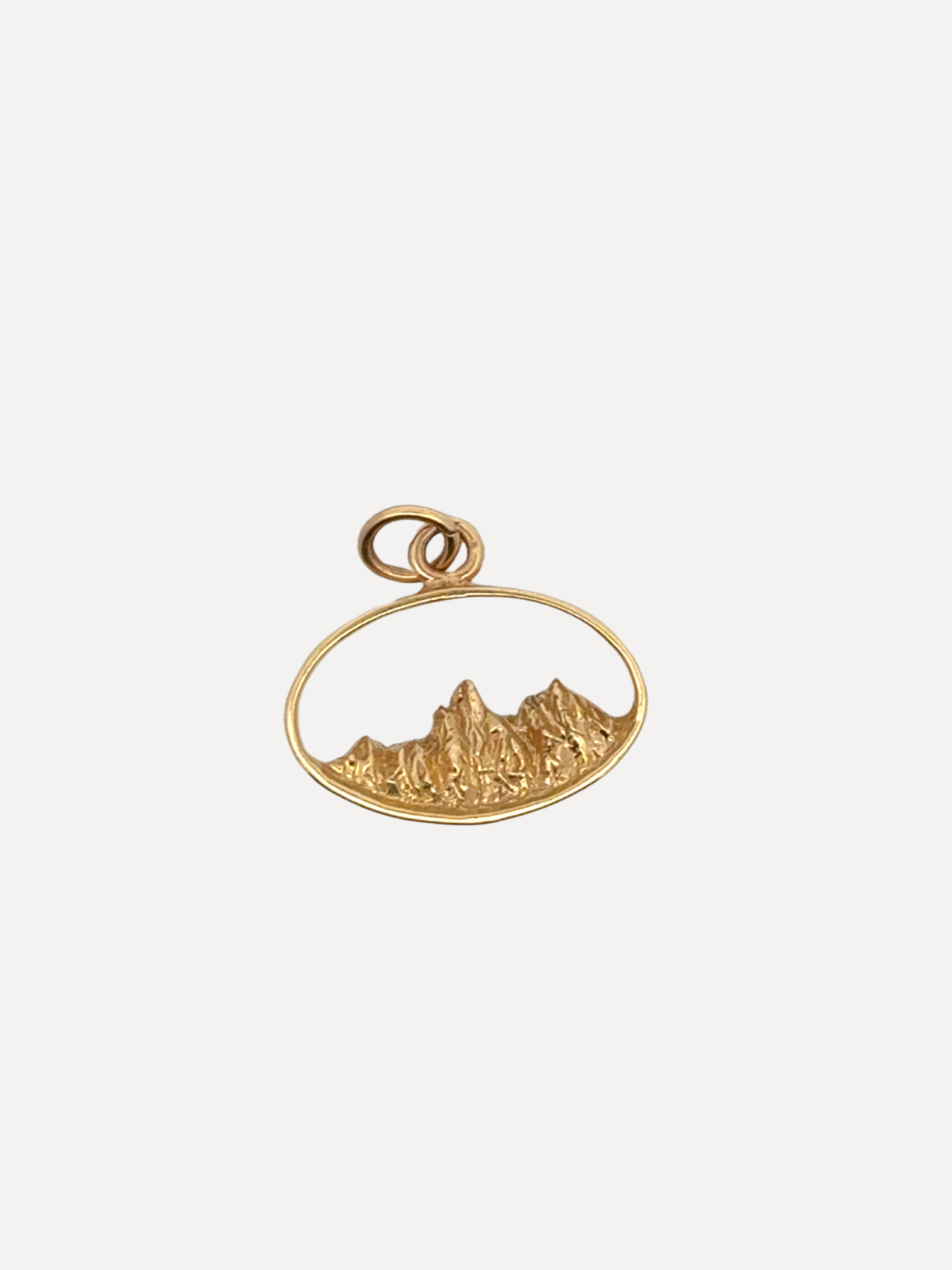 Gold pendant with mountain design on a white background