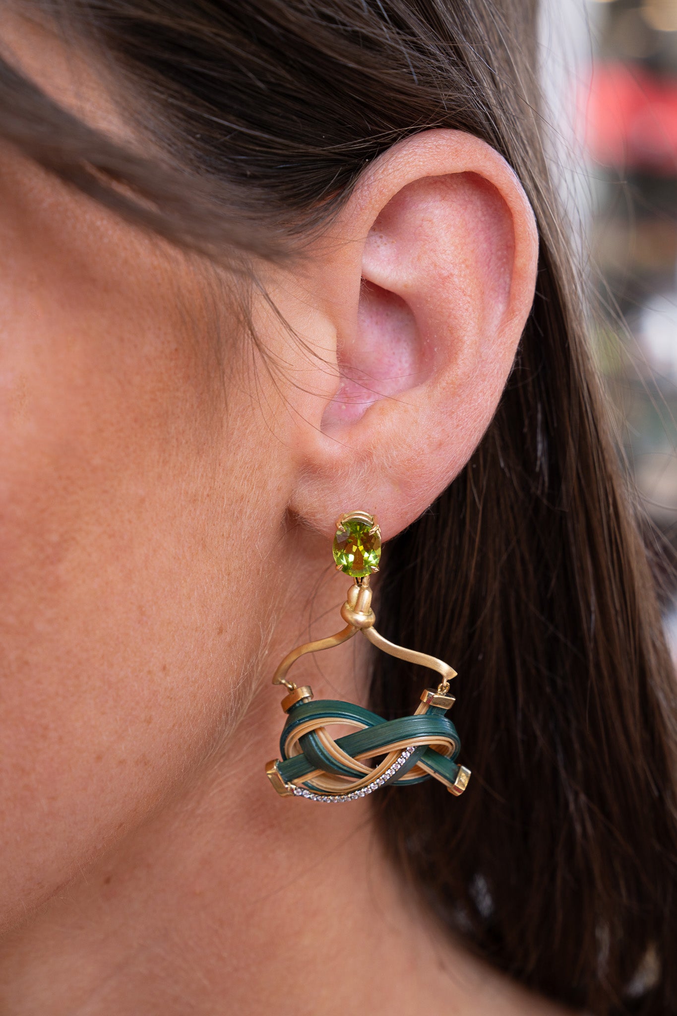 Close-up of an earring with a peridot gemstone worn by a person. Bamboo-Earrings-Silvia-Furmanovich-