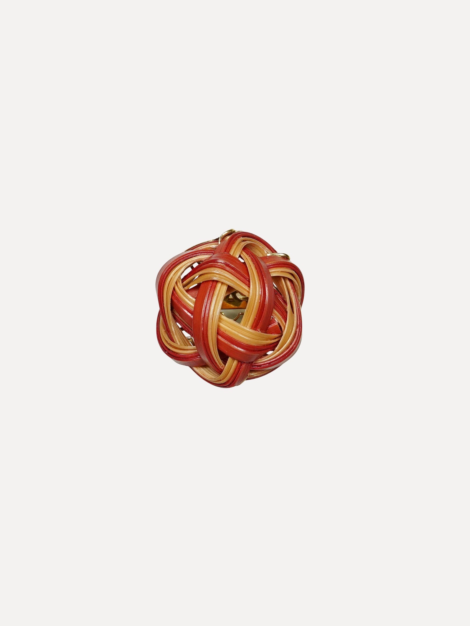 Red and gold woven ball on a white background. Bamboo ring with pink sapphire ring