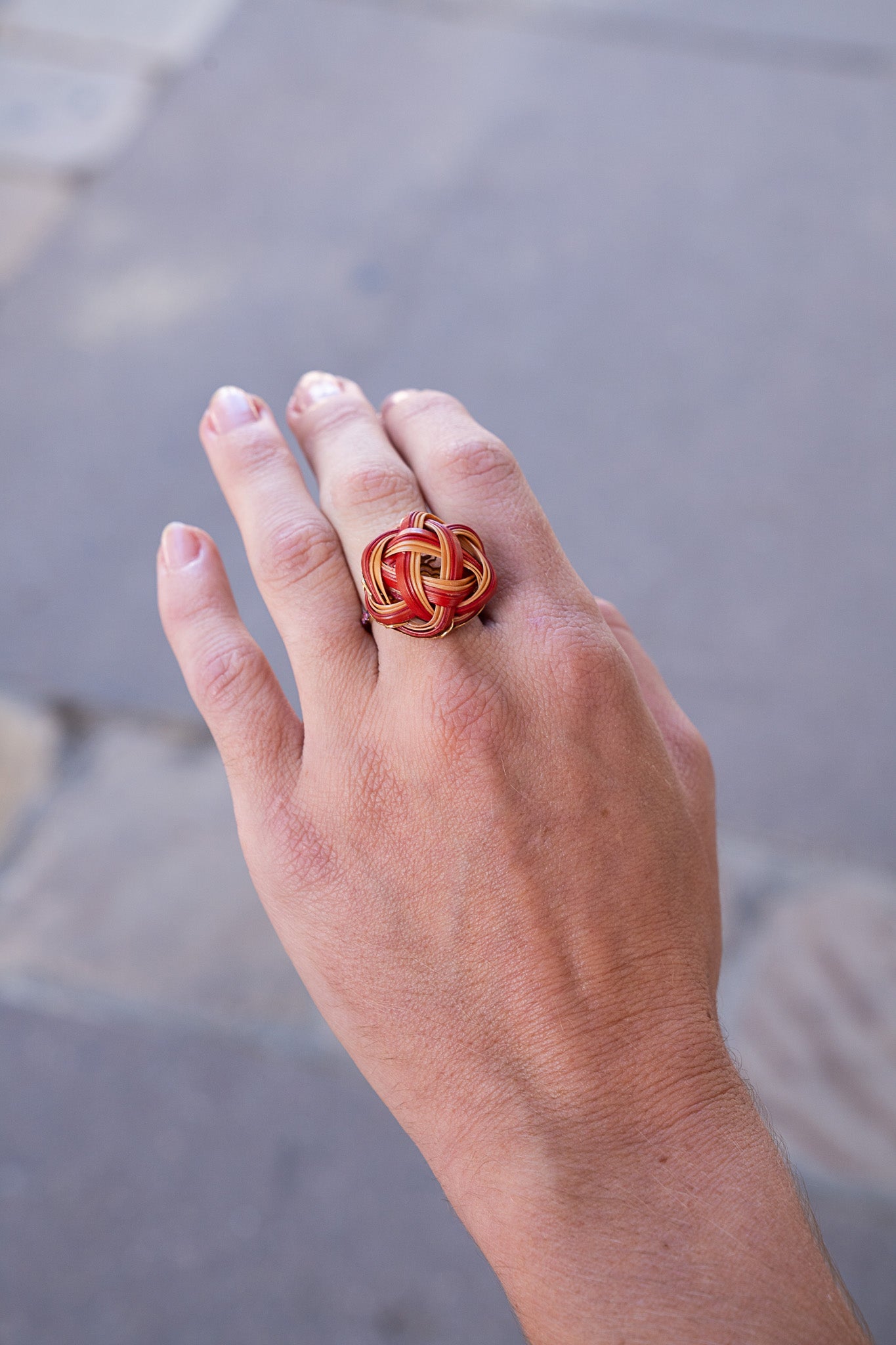 Hand wearing a decorative ring with a blurred background. Bamboo ring with pink sapphire ring