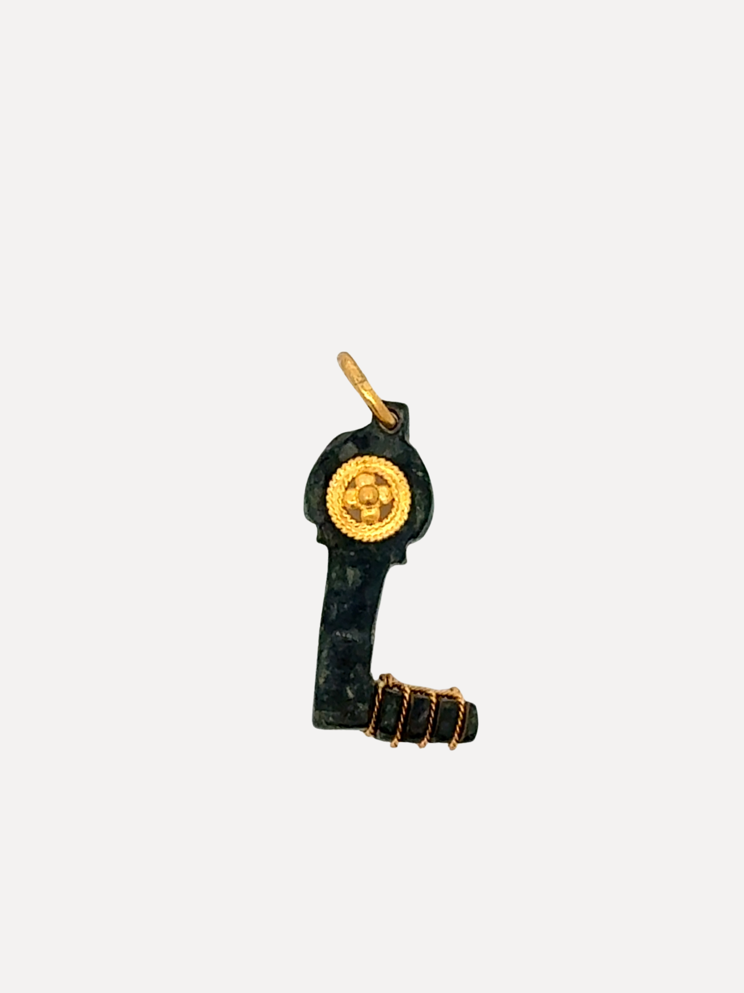 A small bronze key boot-shaped pendant or charm with gold-tone detailing, including a circular medallion and wrap around the sole, shown on a plain light gray background.
