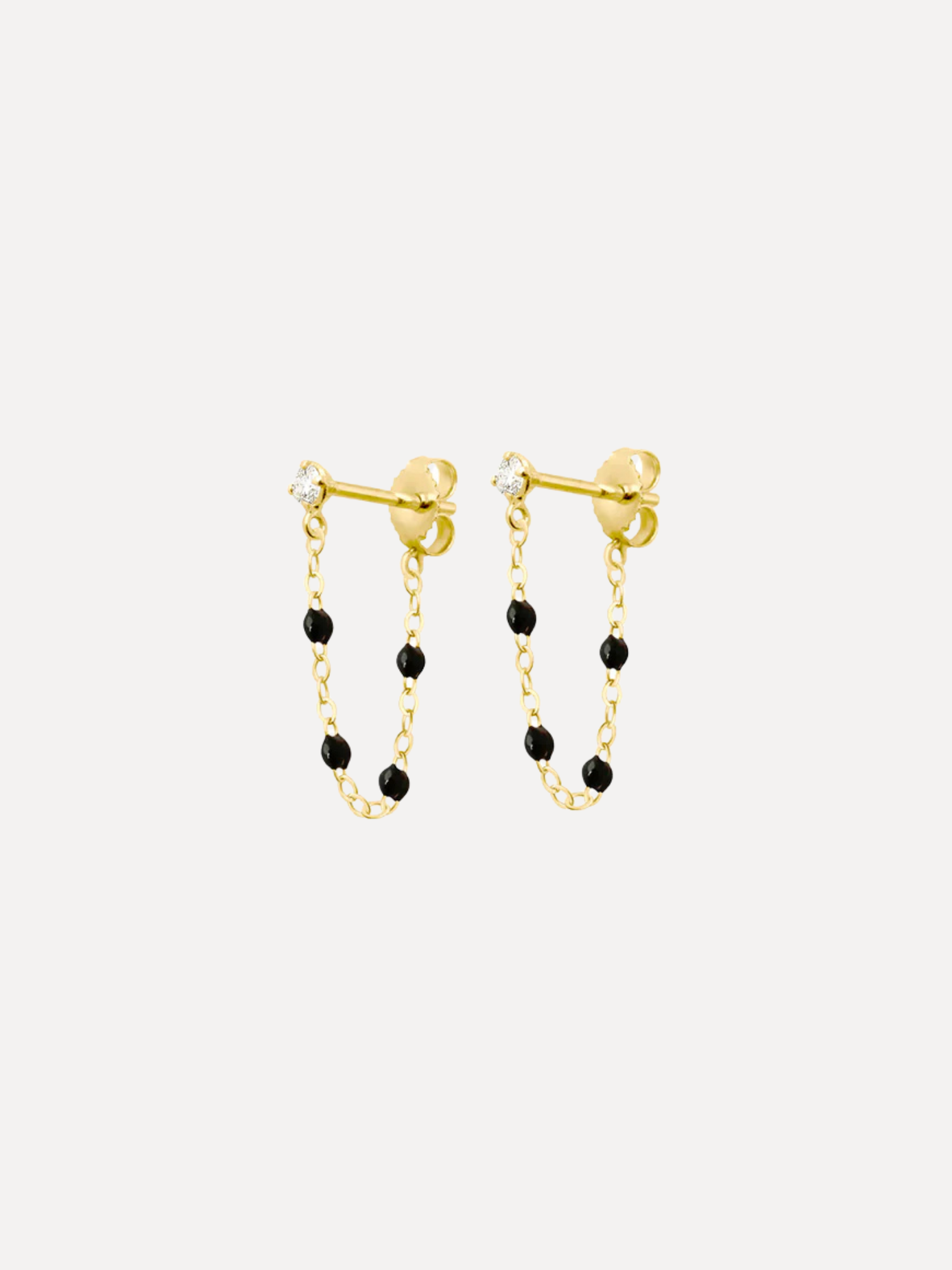 Gold earrings with black beads on a white background