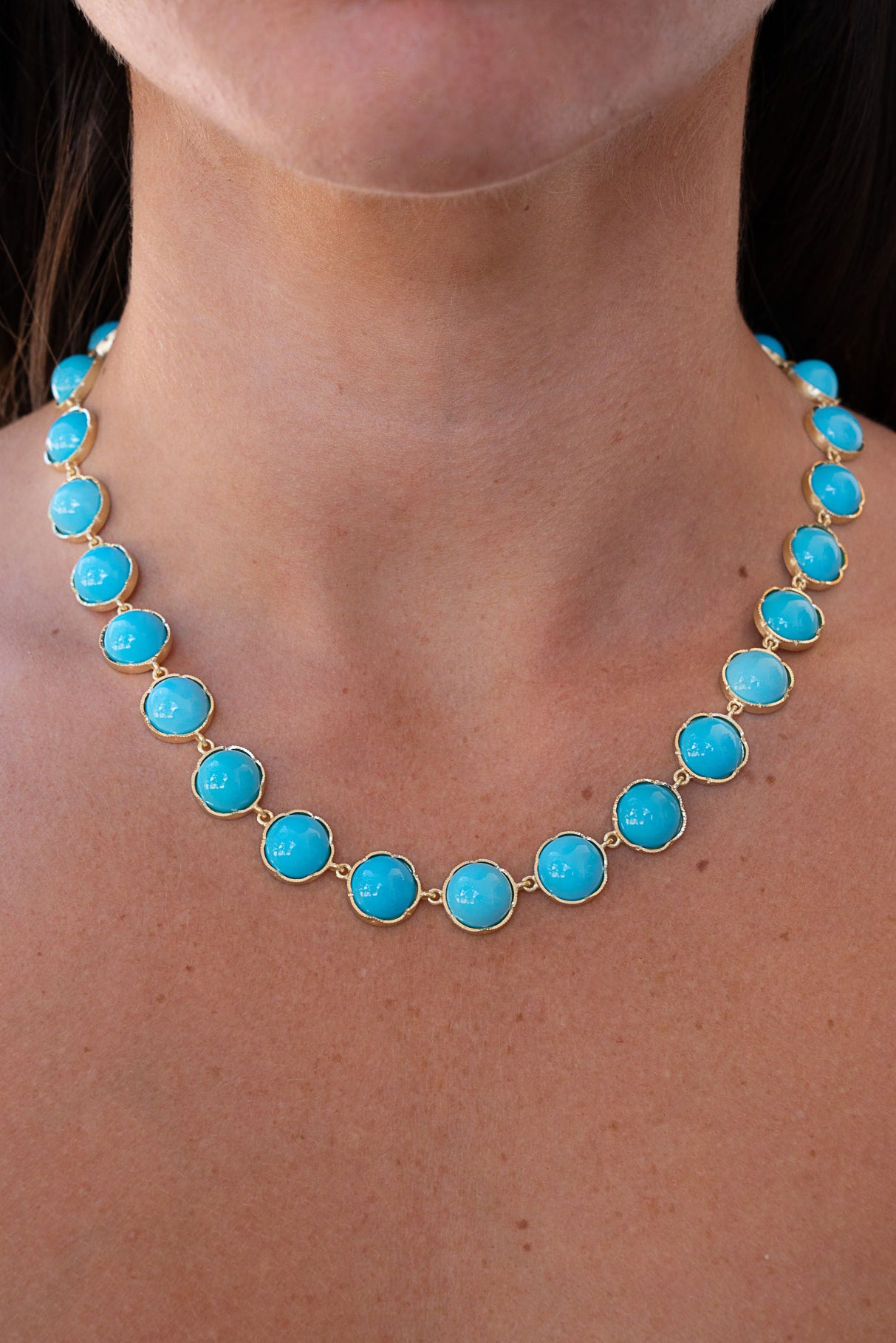 Turquoise necklace with gold accents on a person's neck. Classic Kingman Turquoise Necklace