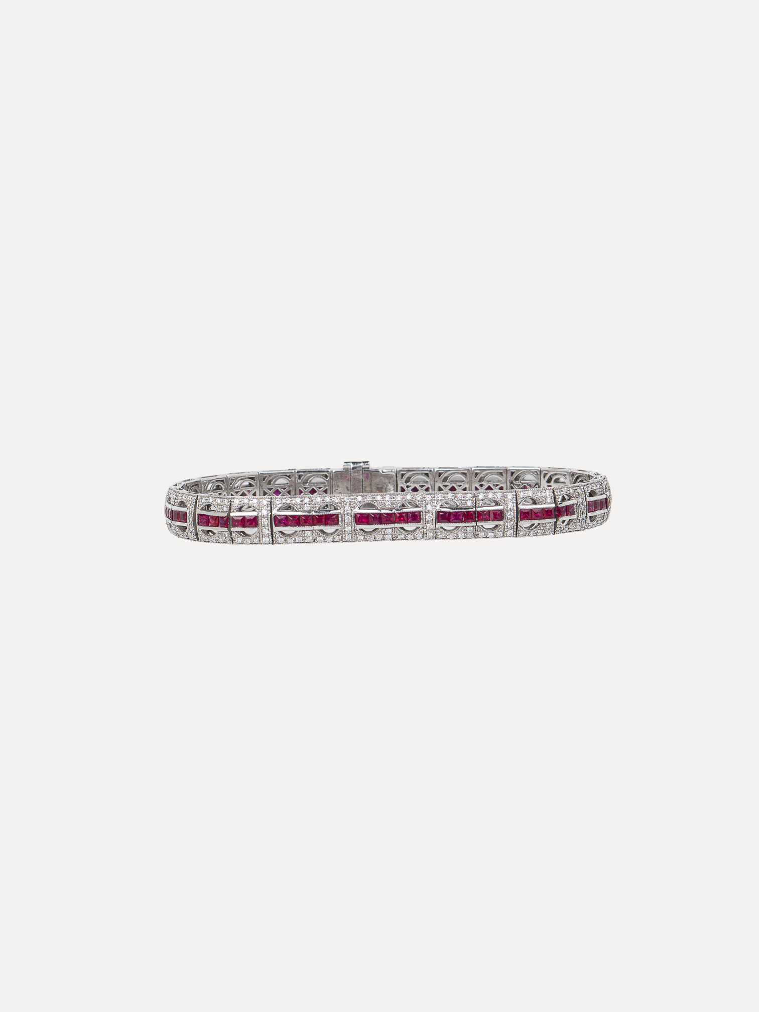 A tennis bracelet featuring a single row of round-cut red gemstones.