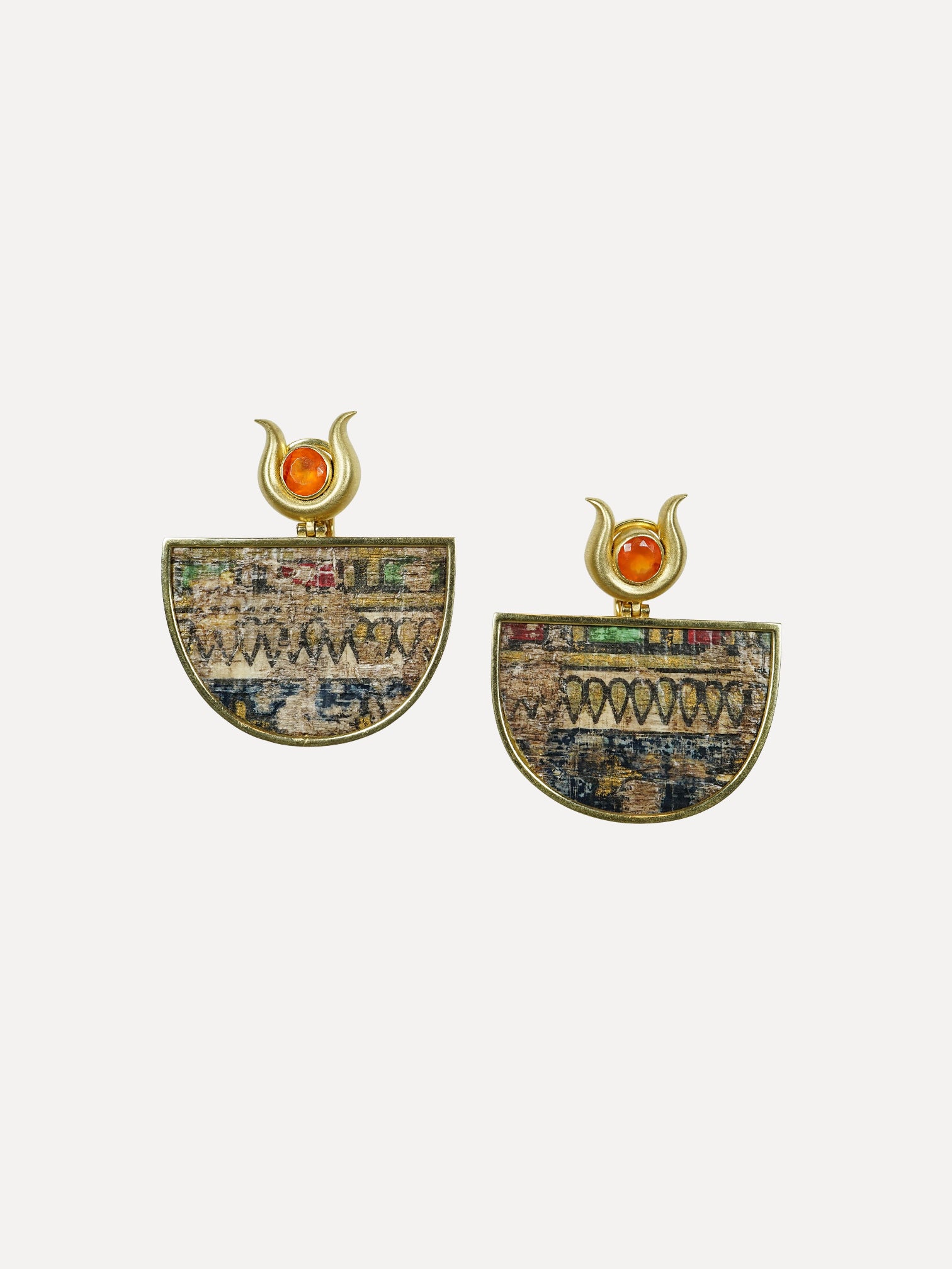 Pair of earrings with intricate designs and orange gemstones on a white background. Egypt Earrings