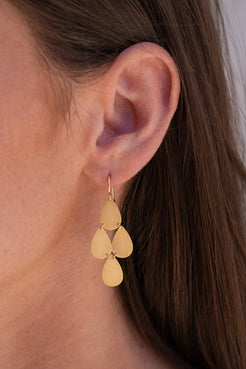 Gold earrings worn by a person with brown hair. Flat_Gold_4_Drop_Chandelier_Earrings Irene Neuwirth