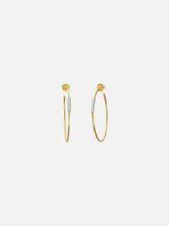 Gold hoop earrings with embedded stones on a light beige background