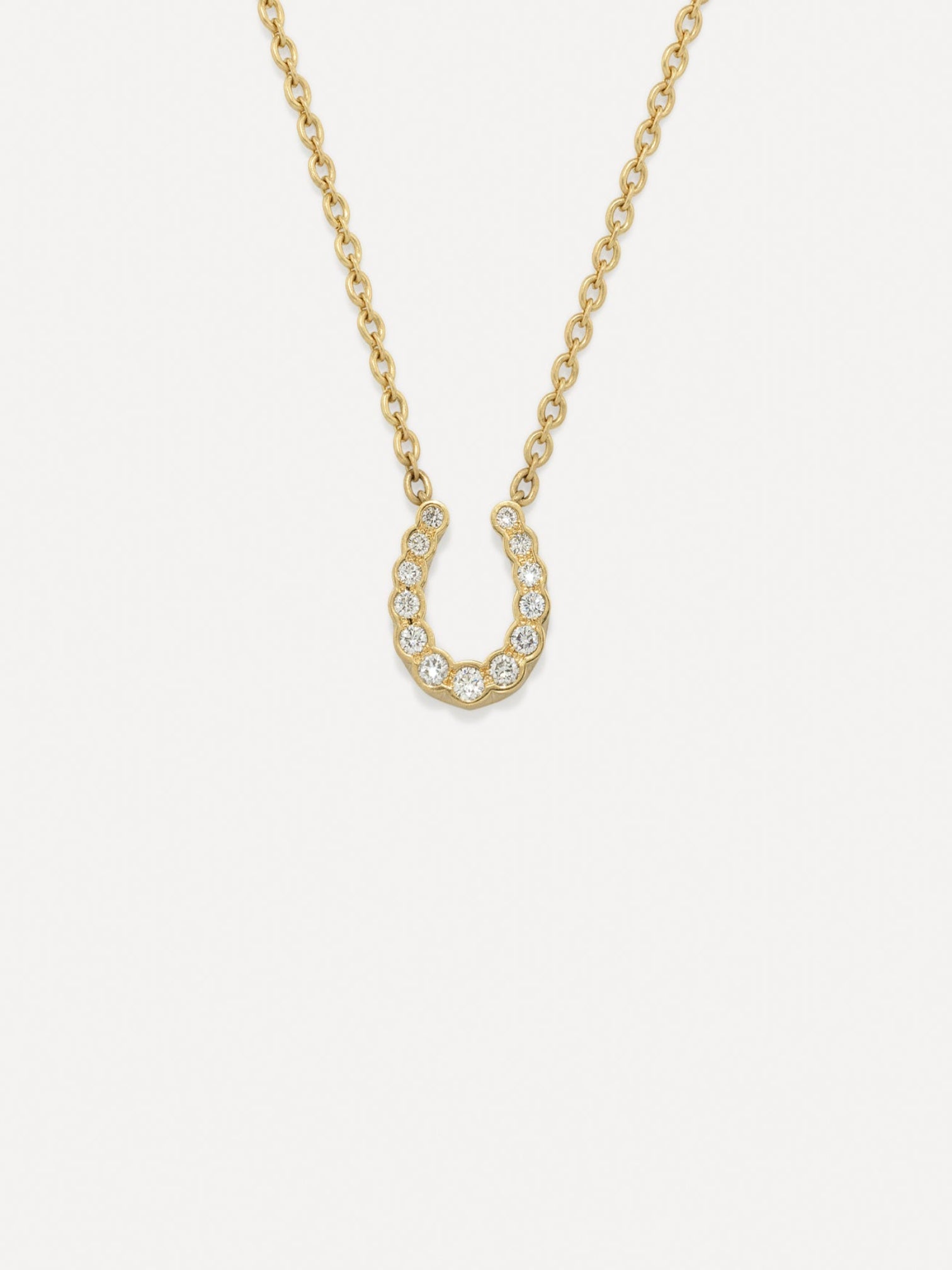 Gold necklace with a horseshoe-shaped pendant on a white background