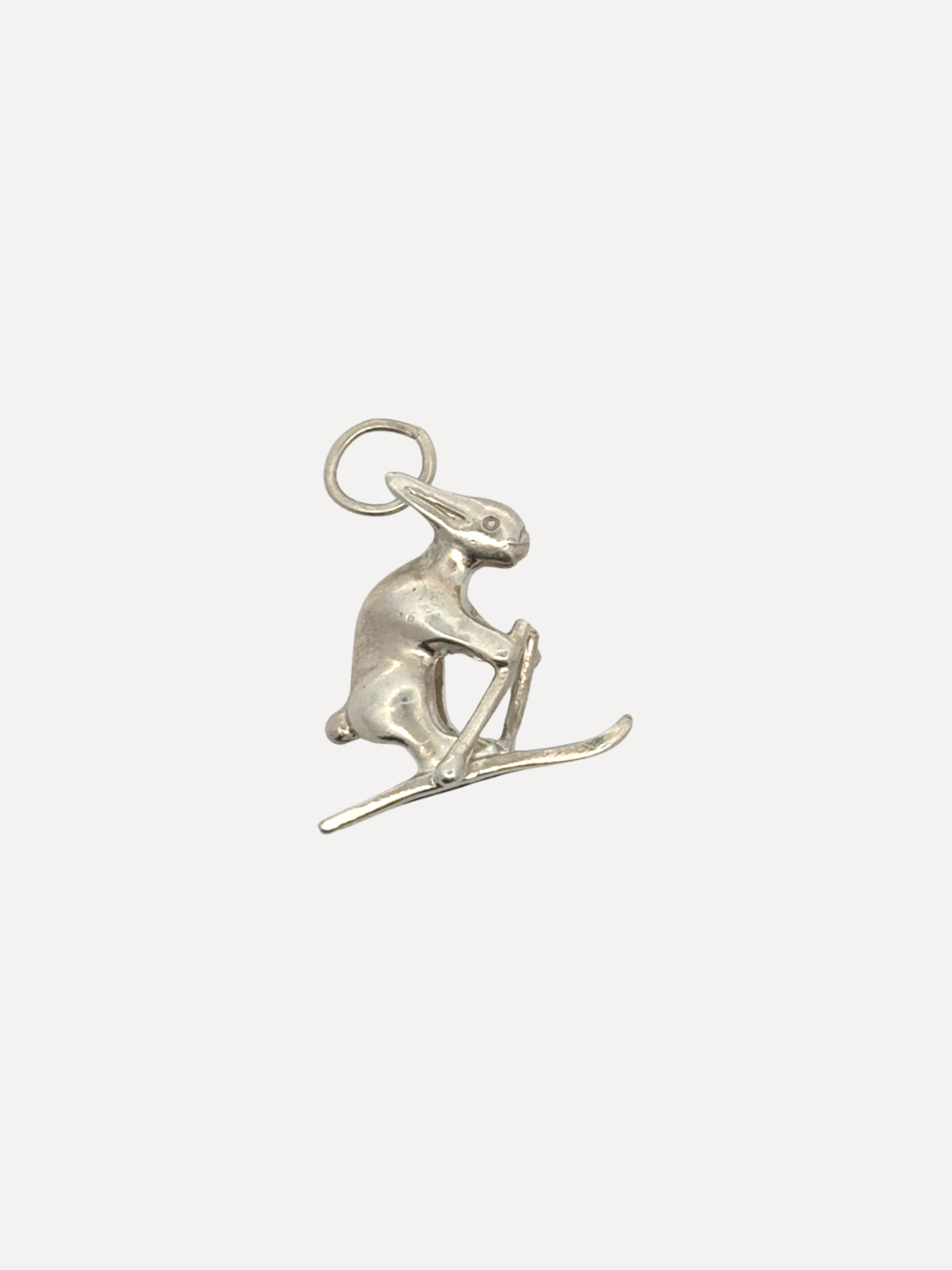 Silver charm of a seal on skis on a white background