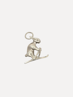 Silver charm of a seal on skis on a white background