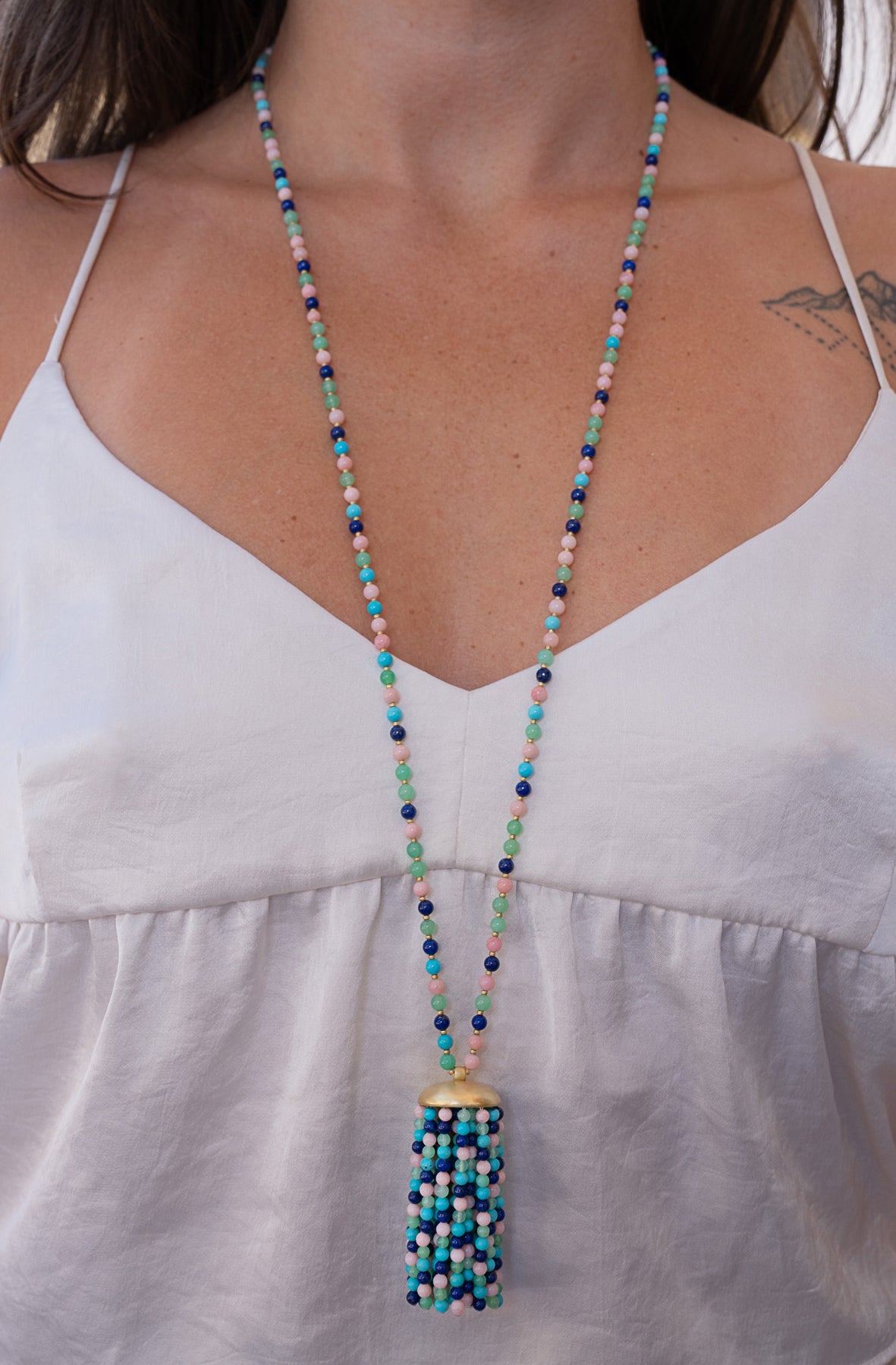 Beaded necklace with tassel worn by a person in a white top. Irene Neuwirth