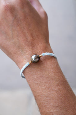 Bracelet with a large pearl on a wrist against a neutral background