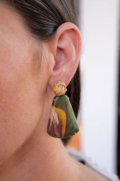 Close-up of a person wearing a colorful earring with a blurred background. Marquetry-Leaf-Pattern-Earrings-Silvia-Furmanovich-190493052