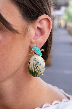 Close-up of a woman wearing a floral earring with a blurred street background. Marquetry_flower_earrings_with_diamonds_and_amazonita_stone
