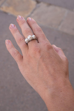 Hand wearing a silver ring with pearls against a blurred pavement background. OOAK Pave Pearl Three 