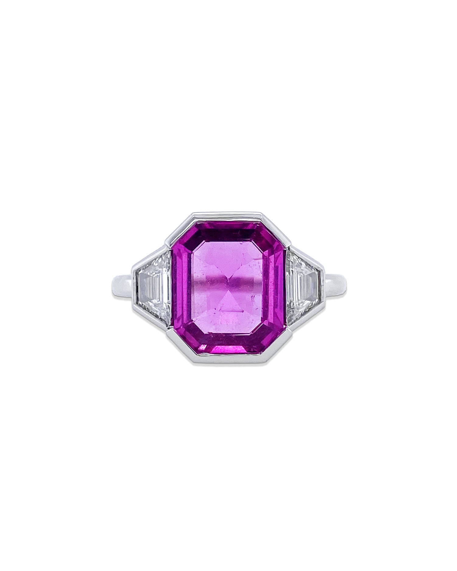 From Bayco's Collection, a platinum ring centered upon a natural unheated emerald-cut Madagascar pink sapphire flanked by colorless trapezoid diamonds, set in a platinum half-bezel surround. The pink sapphire is 3.10 cttws and the diamonds are .61 cttws. 
