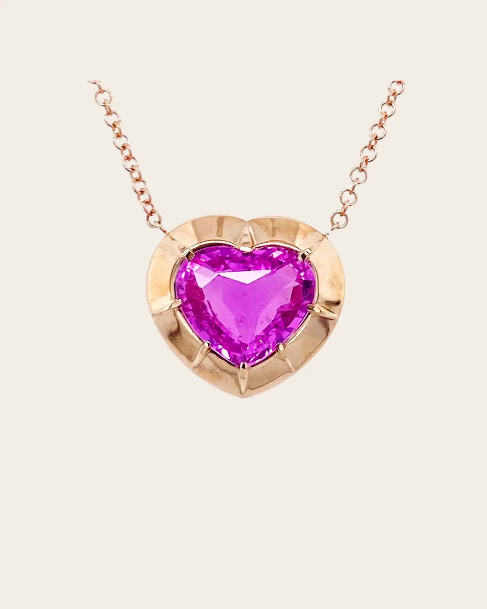 A Bayco rose gold heart pendant with a pink sapphire