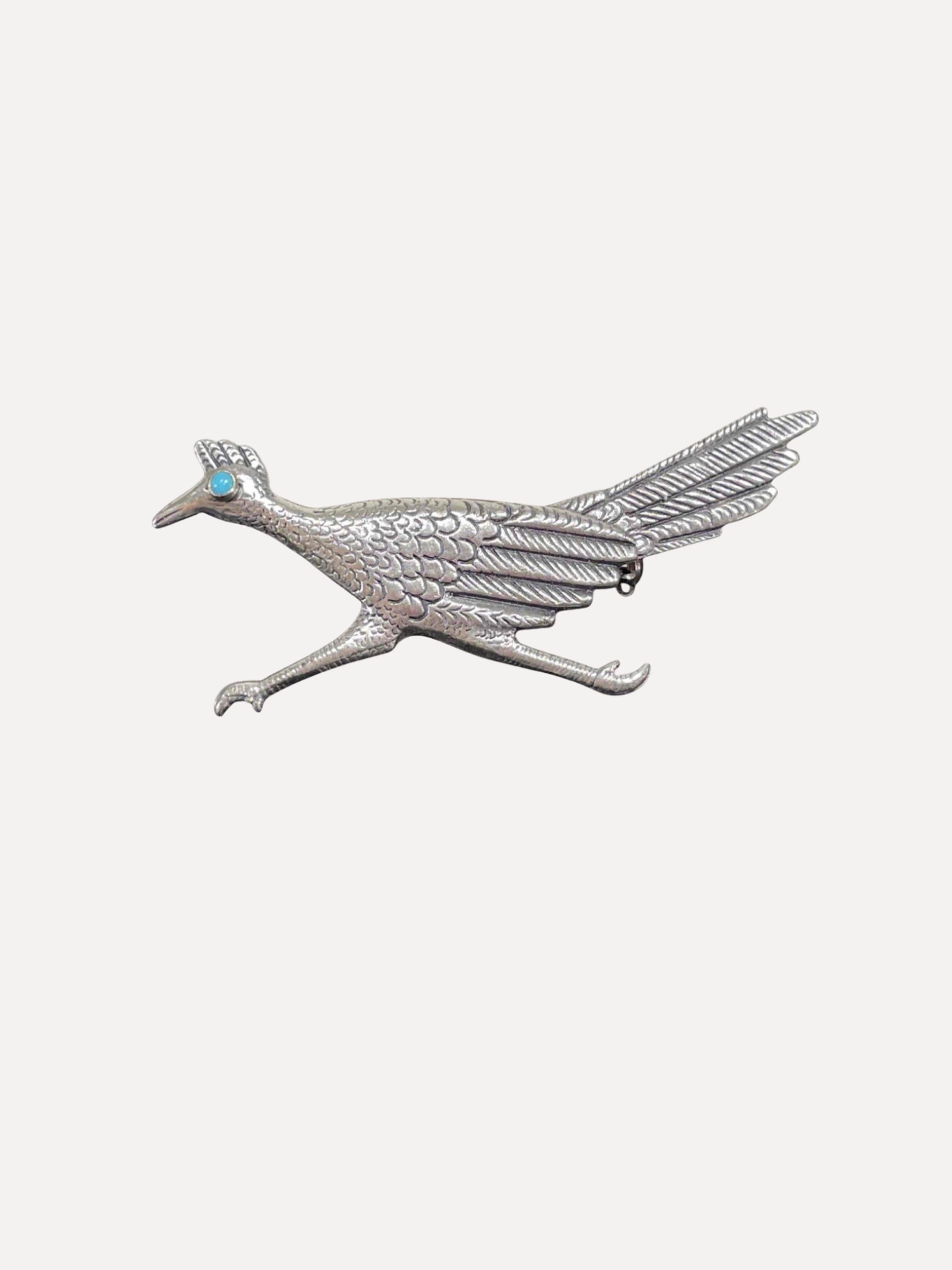Silver bird-shaped brooch with a turquoise stone on a white background