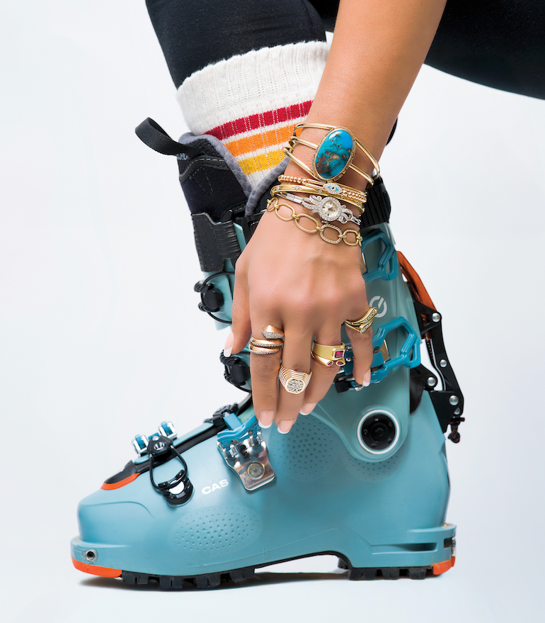 Person adjusting a blue ski boot with colorful accents on a white background