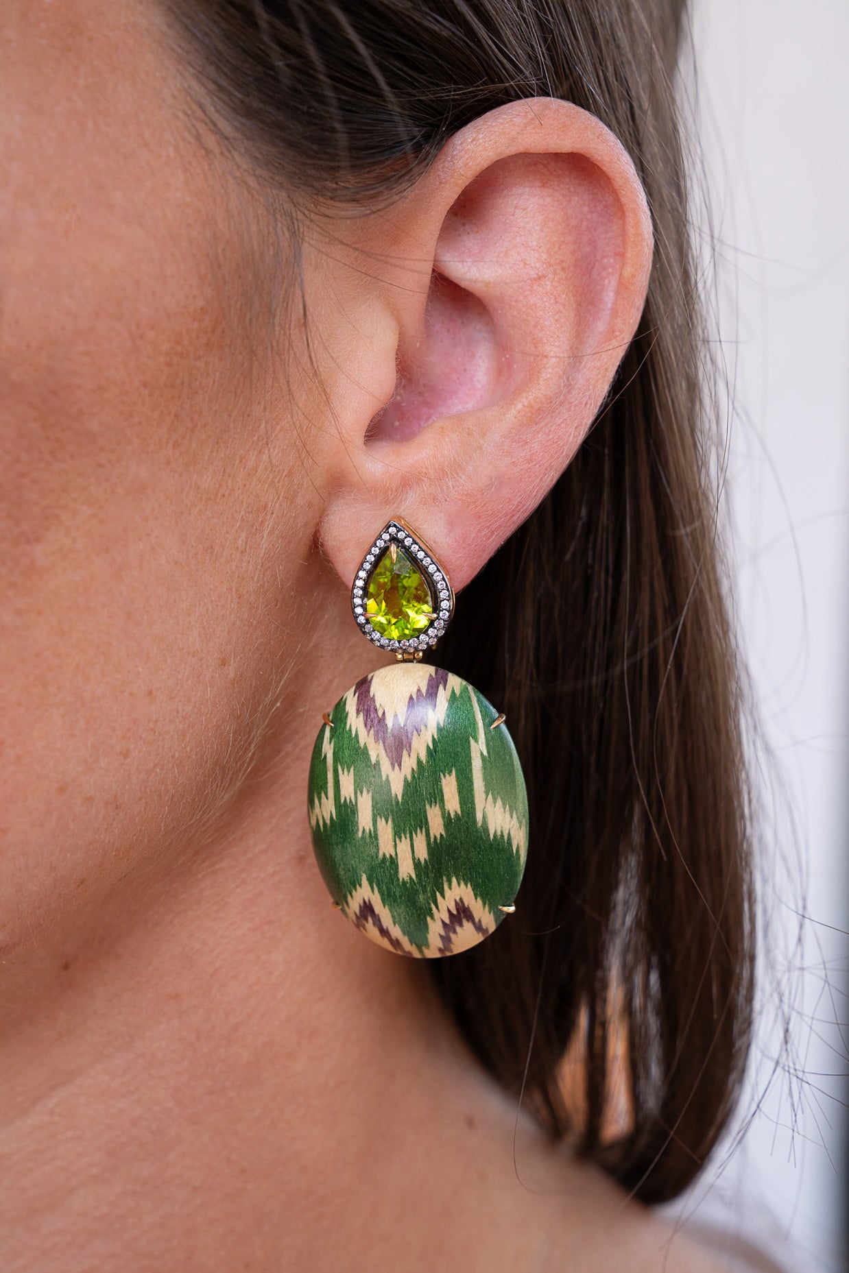 Close-up of a woman wearing a green and gold patterned earring. Silvia Furmanovich Marquetry Green Earrings