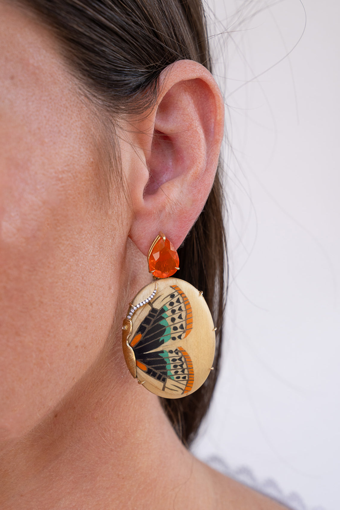 Close-up of a person wearing butterfly-themed earrings with a white background. Silvia_Furmanovich_Mexican_Opal_and_Marquestry_Butterfly_Earrings
