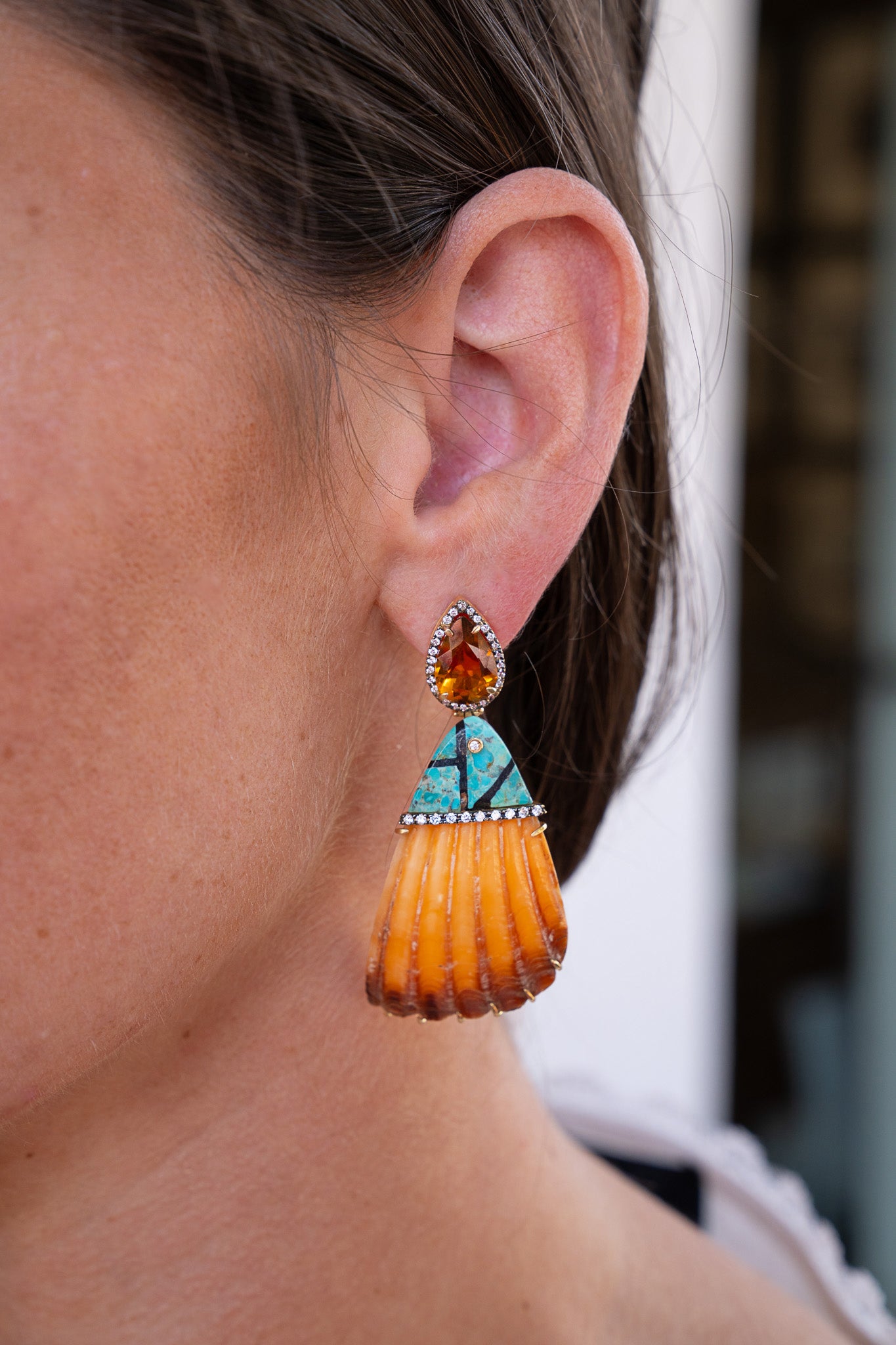 Close-up of a woman's ear wearing an orange and turquoise earring. Silvia_Furmanovich_Shell_Earrings