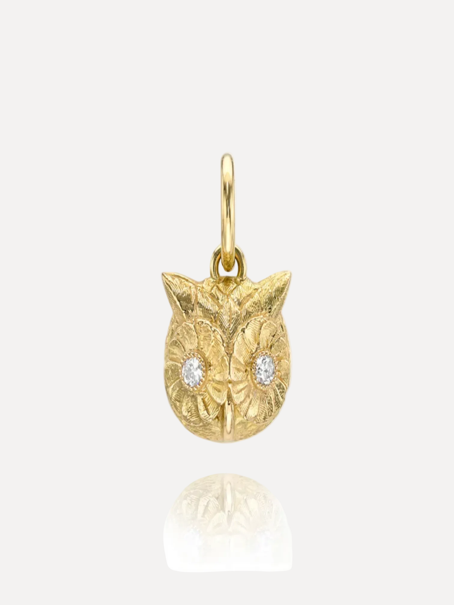 Gold owl pendant with diamond eyes on a white background