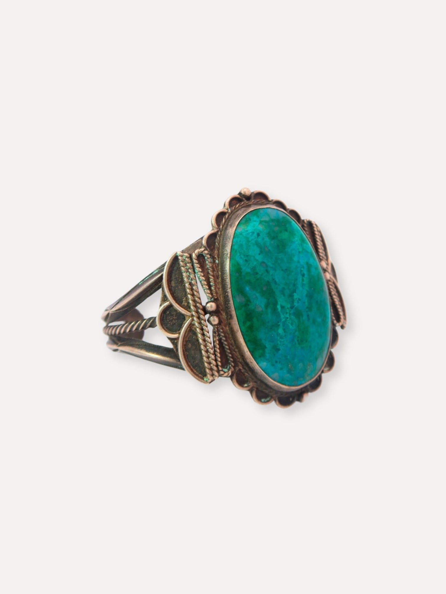 A vintage sterling silver cuff bracelet with a turquoise center and decorative patterns around it.