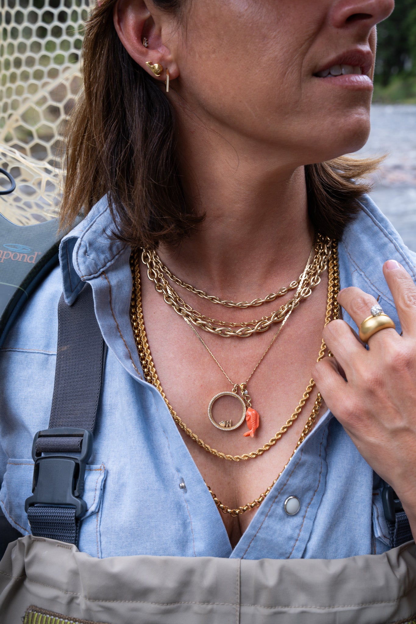 Woman wearing gold necklaces and a ring, with a blurred background