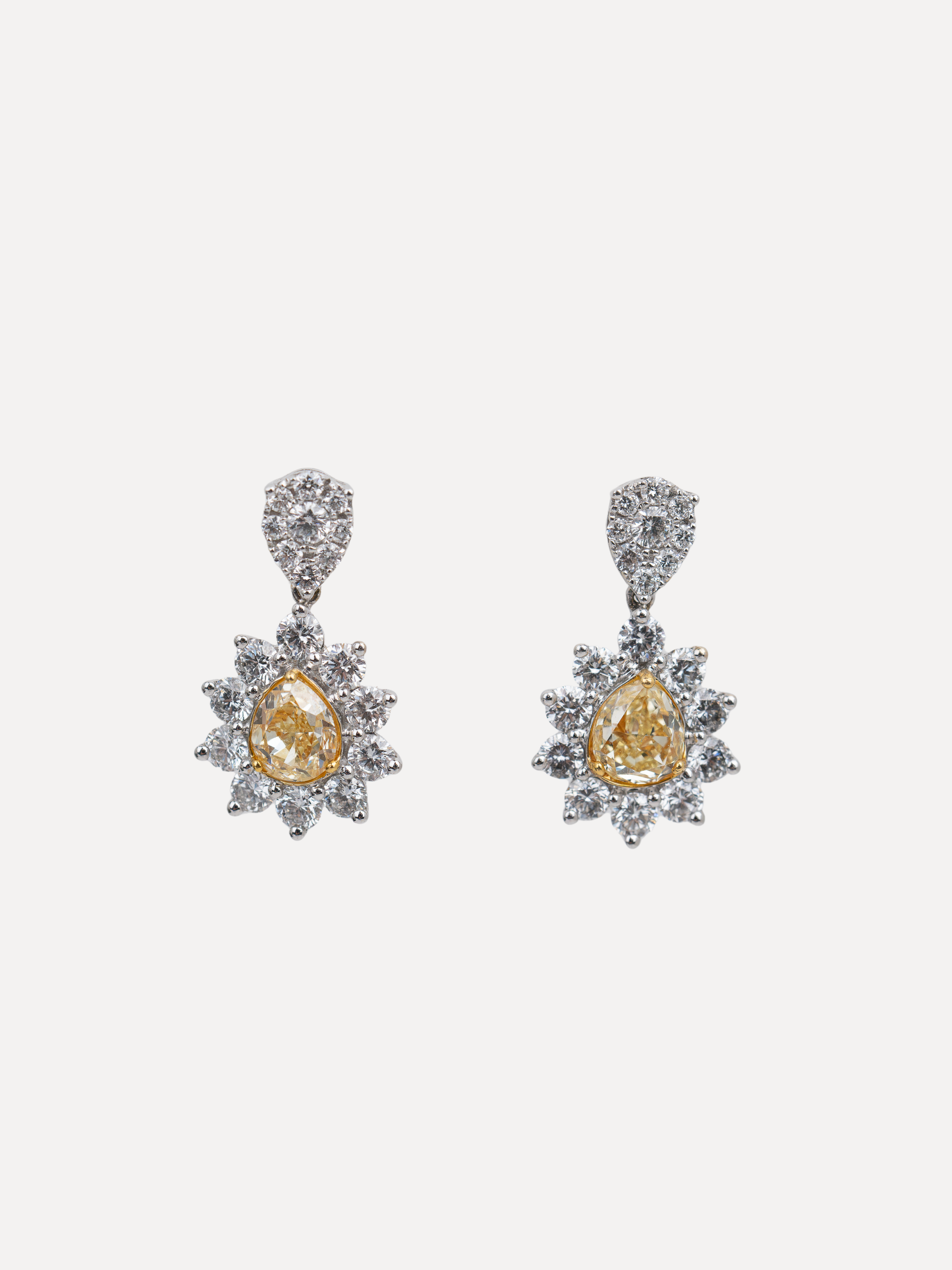 Pair of pear shaped yellow diamond stud earrings on a white background