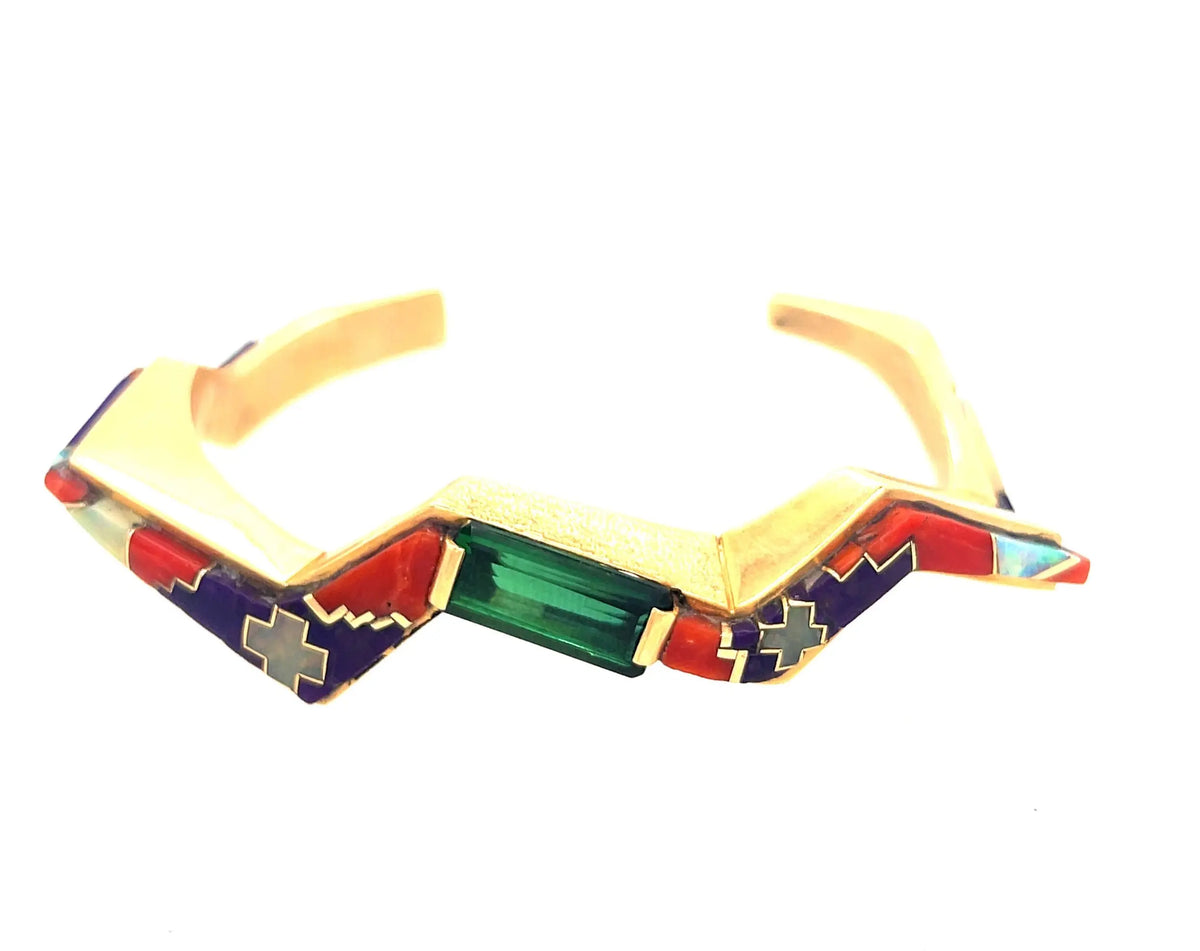 This a very rare Native American cuff with inlay set in 18k yellow gold. There is a large green tourmaline set in the middle with sugilite, coral, opal and mother of Pearl inlay on each side. Native American Artist Danny Romero.